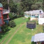 Vista aérea de casa con jardín con trampolín y alberca techada lugar para tus eventos corporativos
